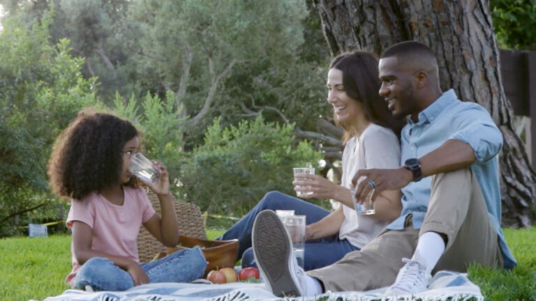 family under tree drinking water