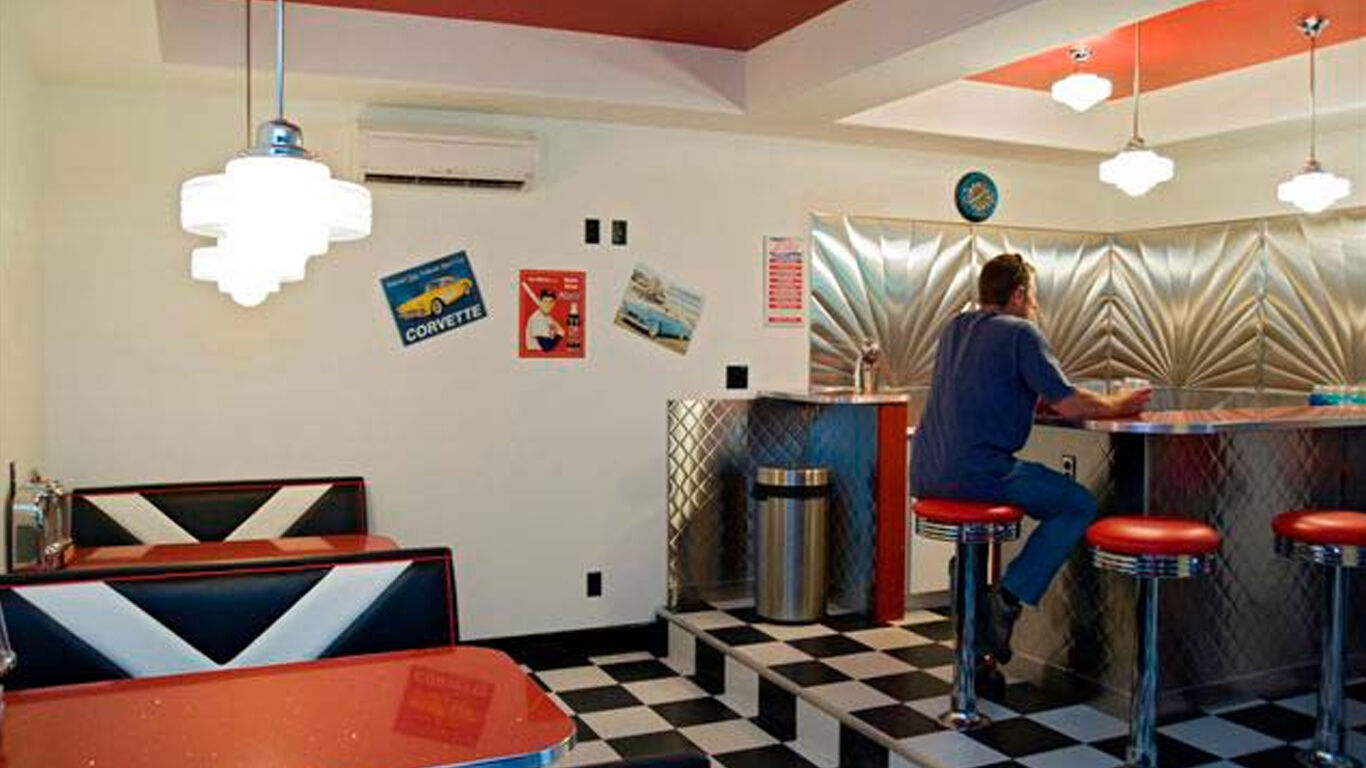 Person sitting at a counter in a retro looking diner.