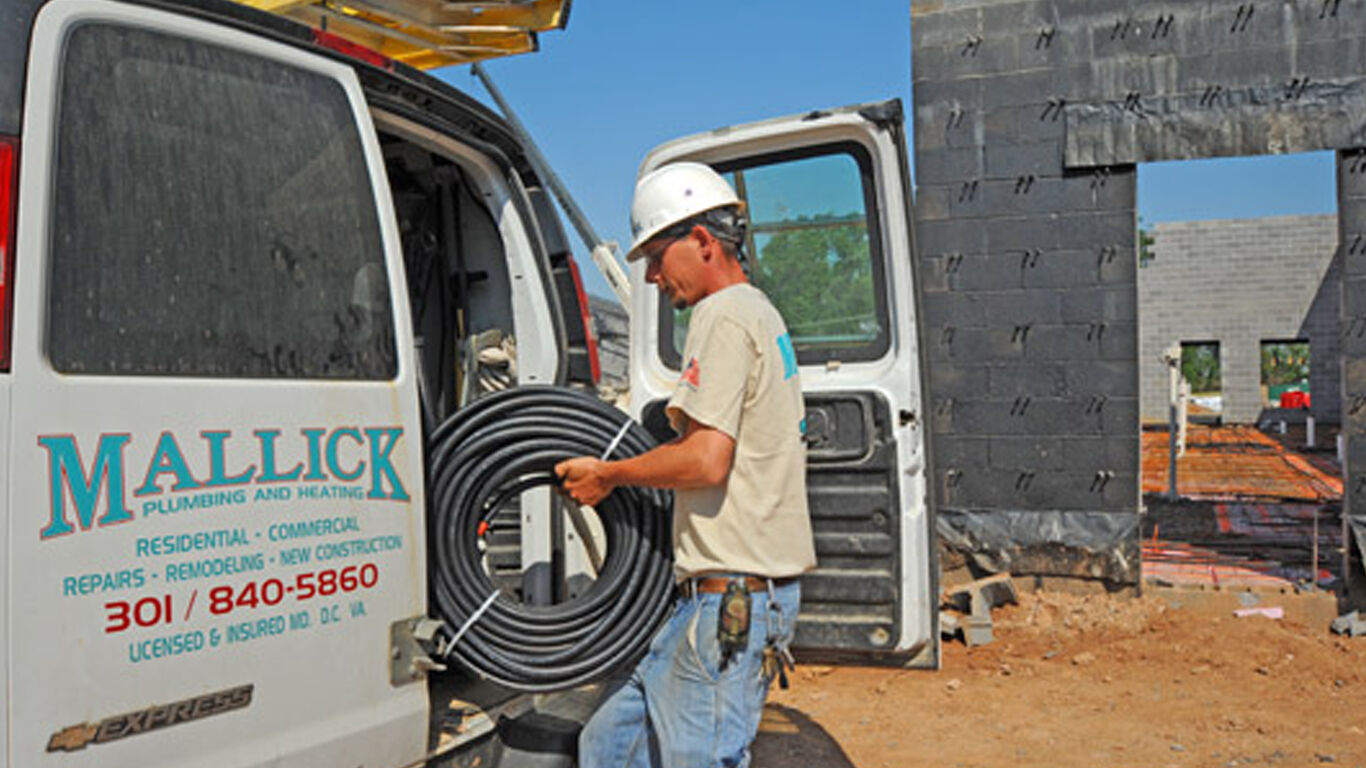 Worker putting a roll of cable into a work truck.