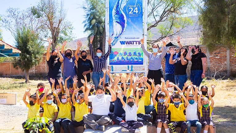 Children and adults with their hands in the air for excitement for water day