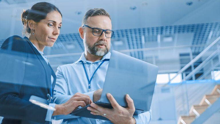 Two facility managers collaborating on a laptop