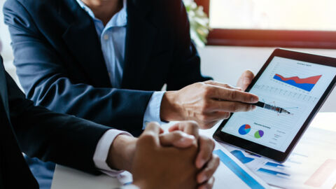 Two men in a business meeting looking at graphs and charts.