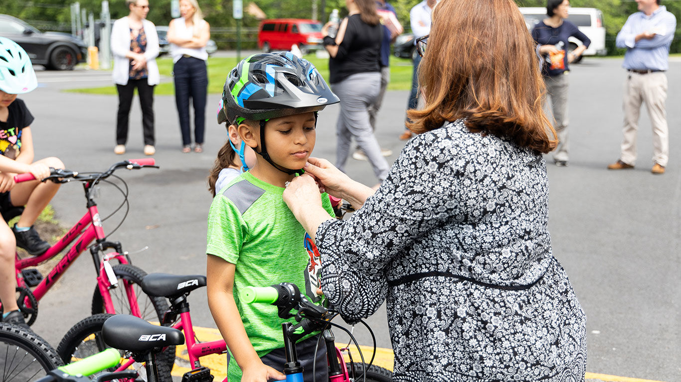 Watts employee helping a child to buckle their helmet.
