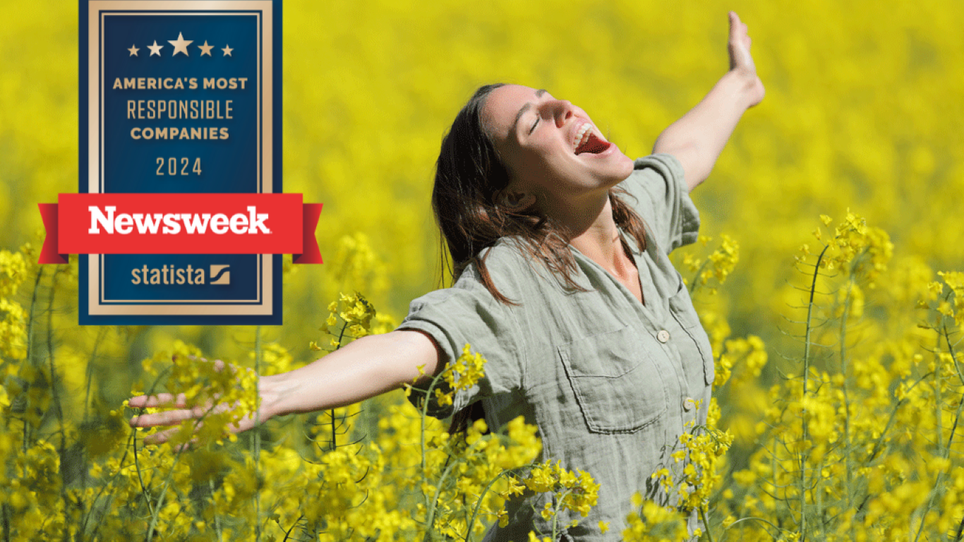 Woman with arms spread and eyes closed in field of flowers. 