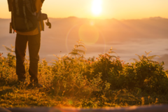 hiker-stand-camping-near-orange-tent-backpack-mountains